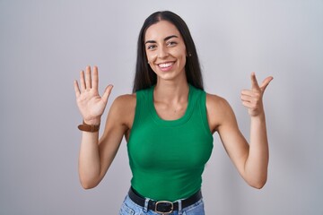 Poster - Young woman standing over isolated background showing and pointing up with fingers number seven while smiling confident and happy.