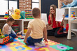 © Krakenimages.com - Teacher with boy and girl sitting on floor having language lesson at kindergarten