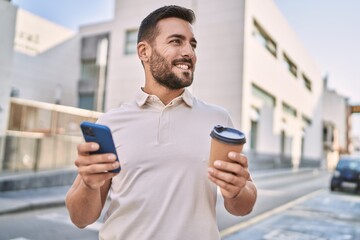 Canvas Print - Young hispanic man using smartphone drinking coffee at street