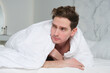 © Евгений Шемякин - Handsome sleepy lazy young man is lying in bed in bedroom covering himself in blanket