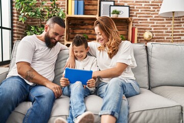 Wall Mural - Family using touchpad hugging each other sitting on sofa at home