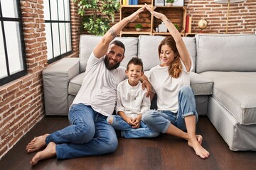 Wall Mural - Family of three doing house shape with arms looking positive and happy standing and smiling with a confident smile showing teeth