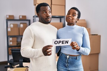 Wall Mural - Young african american couple working at small business ecommerce smiling looking to the side and staring away thinking.