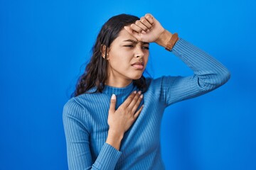 Poster - Young brazilian woman standing over blue isolated background touching forehead for illness and fever, flu and cold, virus sick