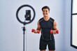 © Krakenimages.com - Hispanic man recording training tutorial at the gym smiling and laughing hard out loud because funny crazy joke.