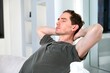 © Евгений Шемякин - Young relaxed handsome calm man is resting, relaxing at home with closed eyes in living room, sitting on couch or sofa with his hands behind head