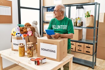 Poster - Senior man wearing volunteer uniform using touchpad at charity center