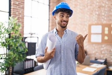 Sticker - Arab man with beard wearing architect hardhat at construction office pointing thumb up to the side smiling happy with open mouth