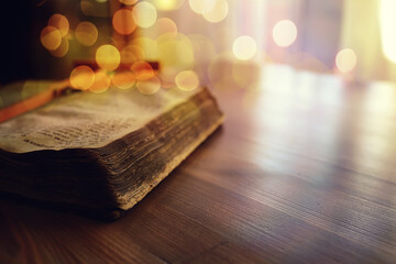 Praying with hand on bible black background. An old book with yellowed pages. Second-hand books.