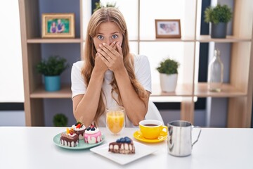 Sticker - Young caucasian woman eating pastries t for breakfast shocked covering mouth with hands for mistake. secret concept.