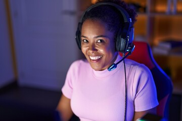 Poster - African american woman streamer smiling confident sitting on table at gaming room