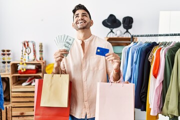 Poster - Young hispanic man holding shopping bags and credit card smiling and laughing hard out loud because funny crazy joke.