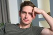 © Евгений Шемякин - Handsome calm relaxed man is sitting on couch or sofa at home in living room looking at camera, resting