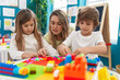 © Krakenimages.com - Teacher with boy and girl playing with construction blocks sitting on table at kindergarten