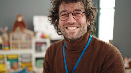 Poster - Young hispanic man preschool teacher smiling confident standing at kindergarten