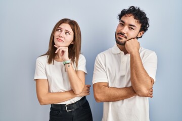 Canvas Print - Young couple wearing casual clothes standing together with hand on chin thinking about question, pensive expression. smiling with thoughtful face. doubt concept.