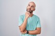 © Krakenimages.com - Middle age bald man standing over white background with hand on chin thinking about question, pensive expression. smiling with thoughtful face. doubt concept.