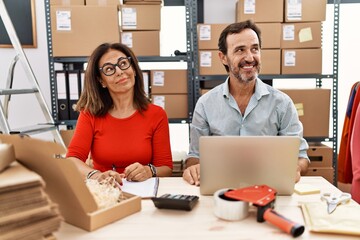 Sticker - Middle age couple working at small business ecommerce smiling looking to the side and staring away thinking.