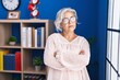 © Krakenimages.com - Middle age grey-haired woman standing with arms crossed gesture at home