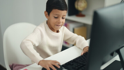 Sticker - Adorable hispanic boy student using computer sitting on table at classroom