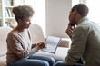 © Prostock-studio - Young black woman psychologist having conversation with patient, showing notes