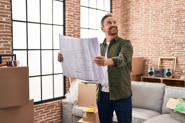 Sticker - Young caucasian man smiling confident looking house plans at new home