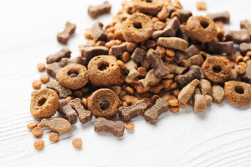 Wall Mural - Dry food for dogs of different shapes on a white wooden background.