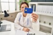 © Krakenimages.com - Young hispanic woman wearing doctor uniform holding credit card at clinic