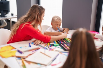 Poster - Teacher and toddler sitting on table drawing on paper at classroom