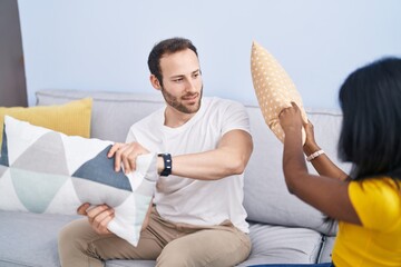 Canvas Print - Man and woman interracial couple fighting with cushion at home