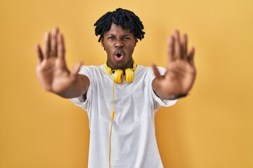 Sticker - Young african man with dreadlocks standing over yellow background doing stop gesture with hands palms, angry and frustration expression