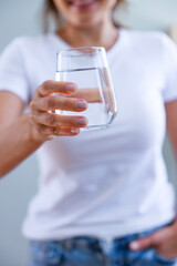 Wall Mural - Young woman showing a full glass of water in her hand