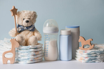 wooden toys, a bear in a bow tie, a stack of diapers, bottles without labels and baby supplies on th