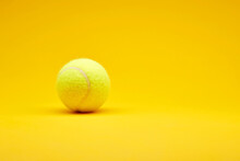 Extreme Close Up Tennis Ball Isolated On The Bright Solid Fond Plain Yellow Background. Sport Inventory And Equipment Concept