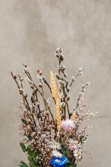 Bouquet of dried wild flowers for Easter - willow twigs, yellow ear of wheat, small white and pink flowers on gray background. Happy holidays. Card with copy space for text