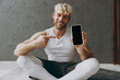 © ViDi Studio - Full body young strong sporty athletic sportsman man wear white tank shirt black shorts hold use point finger on mobile cell phone with blank screen warm up train indoor at gym Workout sport concept.