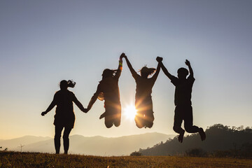 Wall Mural - Silhouette group of happy young people jumping on mountain beautiful summer sunset