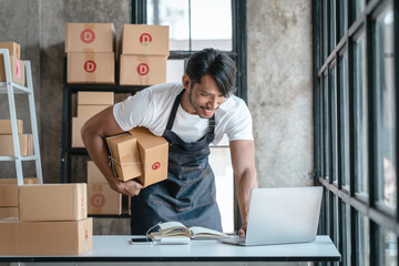 Handsome business sme owners in apron with delivery box package stock warehouse preparing after received online order from customer in social media in laptop, he is influencer.