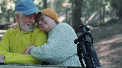 Sticker - Head shot portrait close up of one middle age woman drinking coffee or tea from a cup sitting at table in the nature in the forest of mountain with old husband hugging wife from the back.