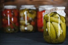 Jars Of Pickled Vegetables On Rustic Wooden Background