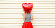 Close Up Woman Covering Her Head With Big Red Heart Shaped Balloon On White Background