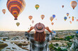 © Goffkein - Girl traveler vacations beautiful destination in Goreme, Turkey. Fabulous Kapadokya with flying air balloons at sunrise, Anatolia