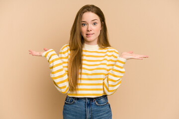 Wall Mural - Young redhead woman cut out isolated confused and doubtful shrugging shoulders to hold a copy space.