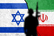 Flags of Israel and Iran painted on the concrete wall with soldier shadow.