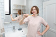 © Vitaliy - Portrait of attractive woman brushing teeth in the bathroom. Morning routine concept