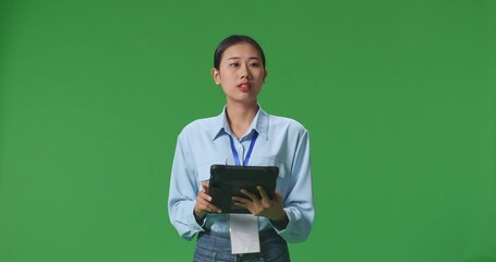 An Asian Business Woman Using Tablet An Looking Around On Green Screen Background In The Studio
