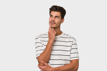 Young handsome caucasian man isolated on white background looking sideways with doubtful and skeptical expression.