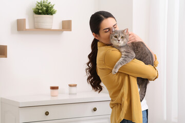 Poster - Young woman kissing her adorable cat at home, space for text