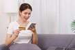 © snowing12 - Lifestyle in living room concept, Asian woman holding credit card and use phone to online shopping