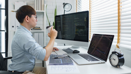 Wall Mural - software development concept, male programmer checking website programming and drinking coffee